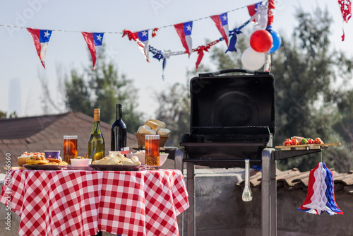 Chilean Independence Day: Outdoor barbecue and traditional food setup with empanadas, completos, wine and patriotic decorations