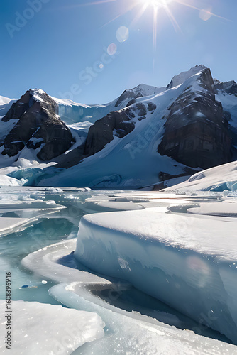 Majestic snow-covered mountains overlook a frozen landscape with icy water channels under a bright sun.