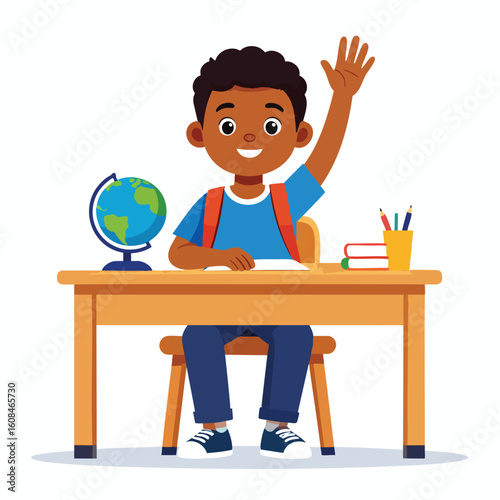 A young, smiling, dark-skinned boy raises his hand while sitting at a desk in a classroom setting.