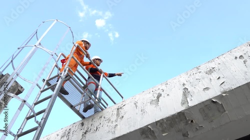 A technician or engineer safely climbs a rooftop ladder wearing full safety gear including helmet and harness, following safety protocols to complete technical inspection and maintenance at height.