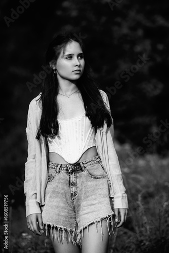 Portrait of a young beautiful dark-haired girl in the forest. Vintage black and white photo.