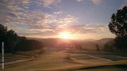 Scenic golf course at sunrise with rolling hills and vibrant sky  