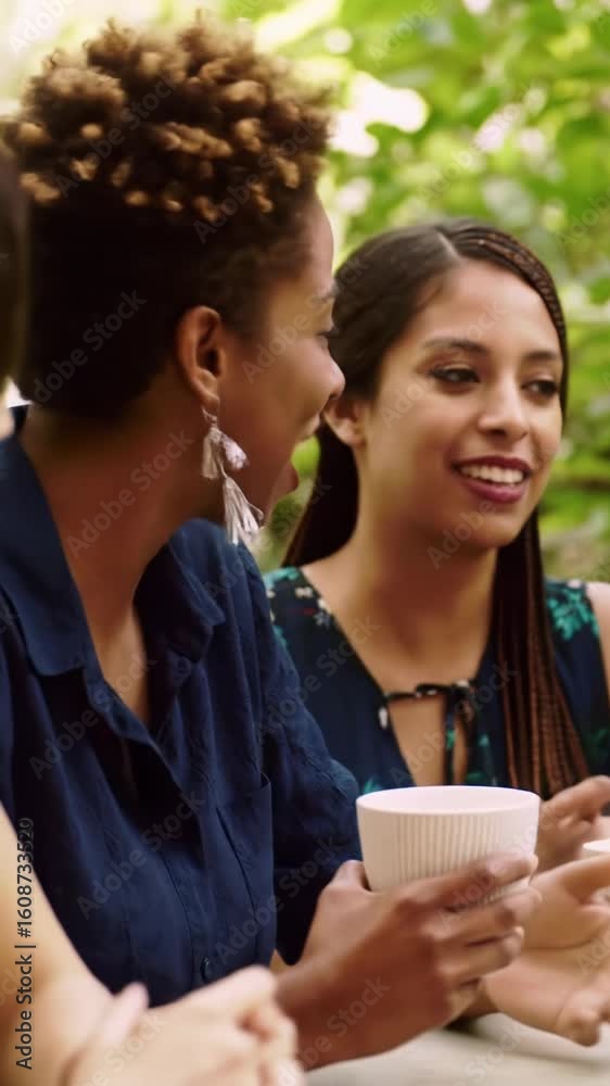 Two to three diverse women, late 20s-early 40s, in joyful, lively conversation at a sun-drenched outdoor cafe with lush green foliage and golden light, holding minimalist coffee cups. concept of joy Two to three diverse women, late 20s-early 40s, in joyful, lively conversation at a sun-drenched outdoor cafe with lush green foliage and golden light, holding minimalist coffee cups. concept of joy