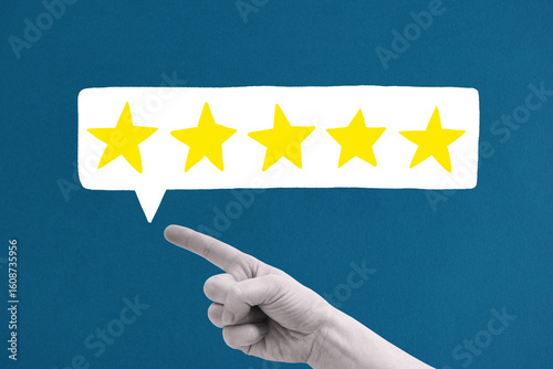 Hand zeigt auf fünf gelbe Sterne in Sprechblase vor dunkelblauem Hintergrund – Konzeptfoto für Bewertung mit digitalen Gestaltungselementen
