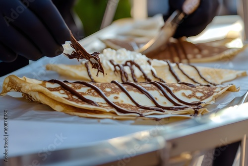 Chic crepe truck with Parisian flair captures Nutella drizzle mid-air over elegantly plated dessert.