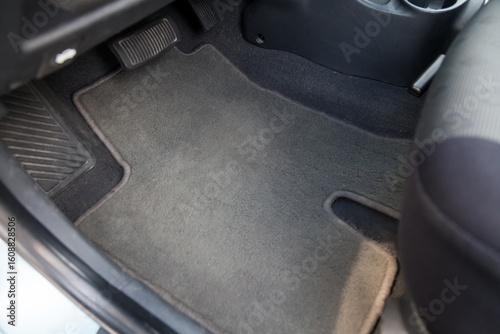 Clean car floor mats of black carpet under front passenger seat in the workshop for the detailing vehicle before dry cleaning. Auto service industry. Interior of sedan.