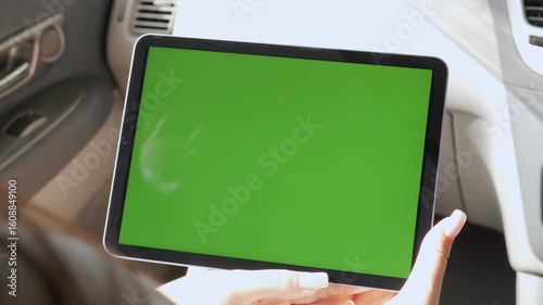 Person is holding a tablet with a green screen. The tablet is in a car