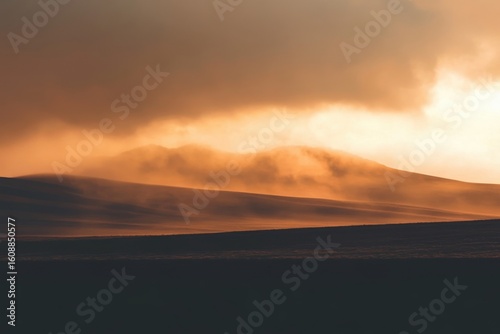 Dramatic landscape with thick clouds covering mountains at sunset for print or poster design