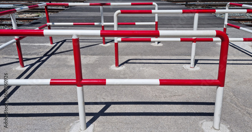 Obraz na plátně A red and white safety barrier in front of train tracks under a clear sky, creat