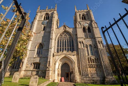 King's Lynn, England. Main west facade of King's Lynn Minster, also known as St Margaret's Church, with twin towers under a sunny sky. Originally founded in 1101 as part of a Benedictine priory
