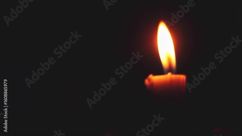 Single candle flame in darkness