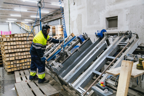 Φωτογραφία Factory worker wearing safety equipment operating machinery for assembling woode