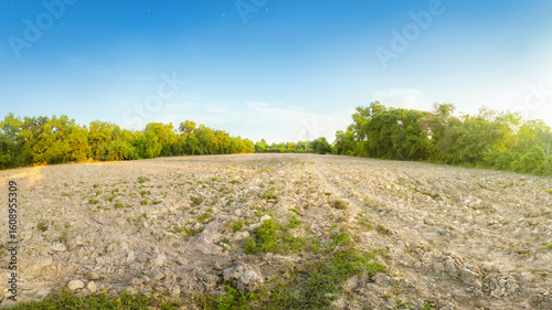 Empty dry cracked swamp reclamation soil, land plot for housing construction project with car tire print in rural area and beautiful blue sky with fresh air Land for sales landscape concept.