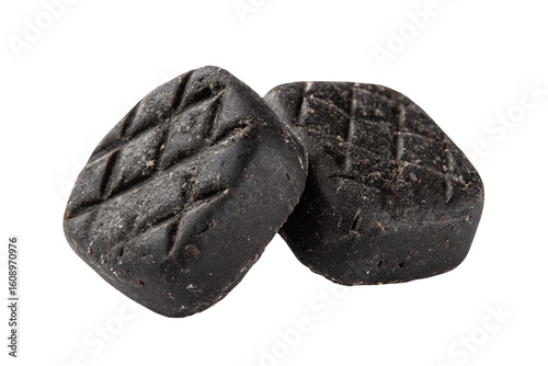 Two textured black charcoal briquettes isolated on a plain black background in close-up view