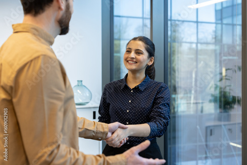 Photography A woman in a blue polka dot shirt shakes hands with a man in an office setting