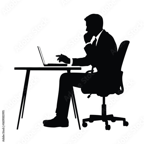 Silhouette of a businessman working on a laptop at a desk