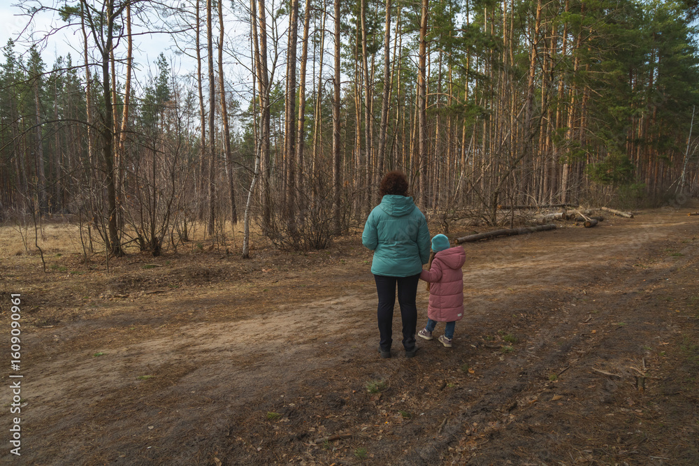 Fototapeta premium Grandmother and granddaughter walking in the forest