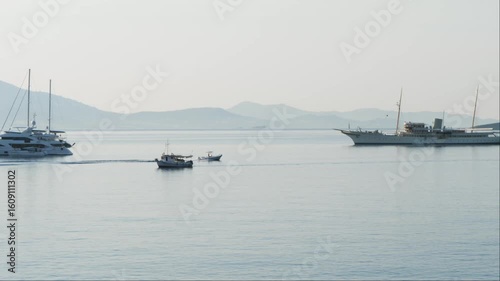 Wallpaper Mural Tranquil seascape in Varkiza, Athens. Calm water reflects a bright sky. Large yachts and small boats sail across the scene. Hazy mountain islands in the background.  Torontodigital.ca