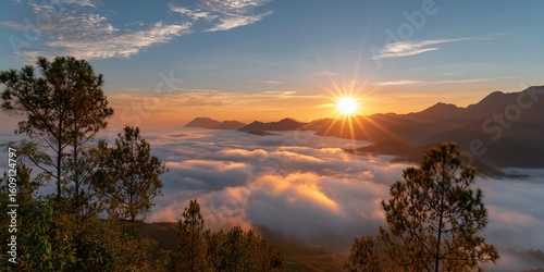 A stunning sunrise over the mountains, with clouds of mist swirling below and sun rays piercing 