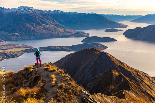 Obraz na płótnie Adventurous hiker girl stands on summit of Roys Peak  admiring breathtaking pano