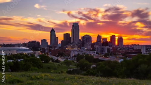 Kansas City Skyline at Sunset with Golden Light Reflecting on Modern Buildings against Cloudy Orange Sky from Grassy Hillside Overview