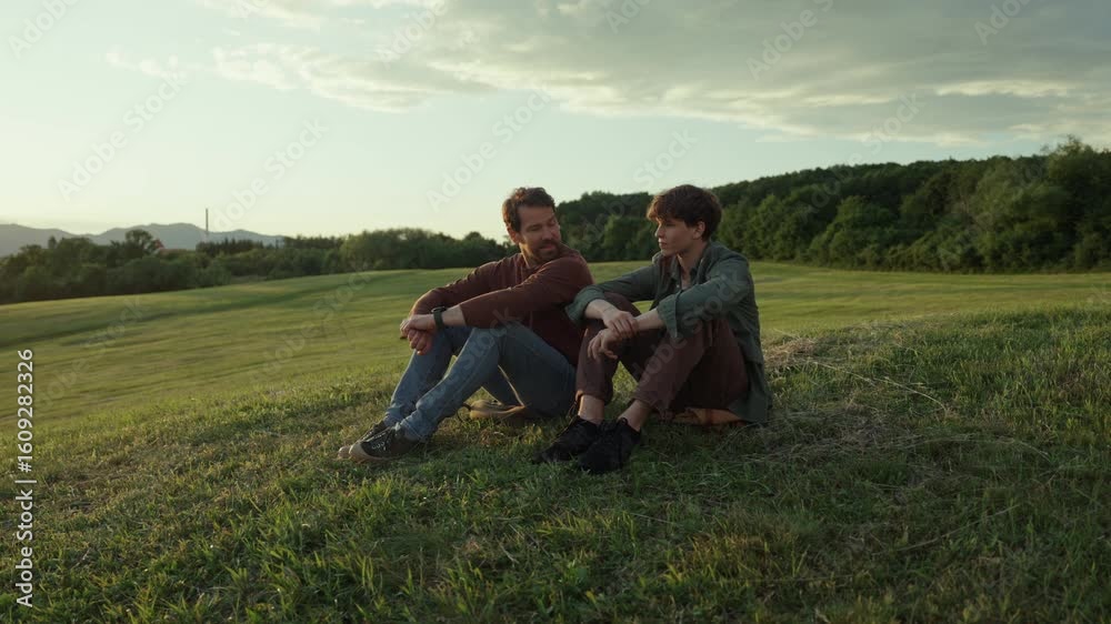 Dad and son resting on hilltop, enjoying scenic view. Dad and son resting on hilltop, enjoying scenic view.