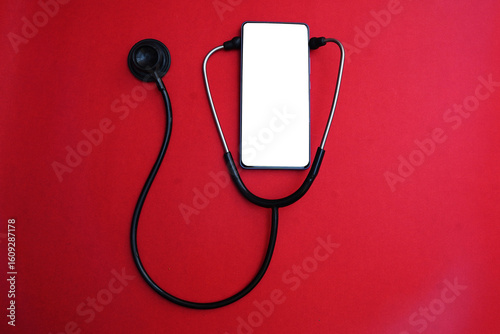             Stethoscope and mockup phone isolated on red background.  Online medical clinic communication with patient. Mockup phone with stethoscope checks health. 