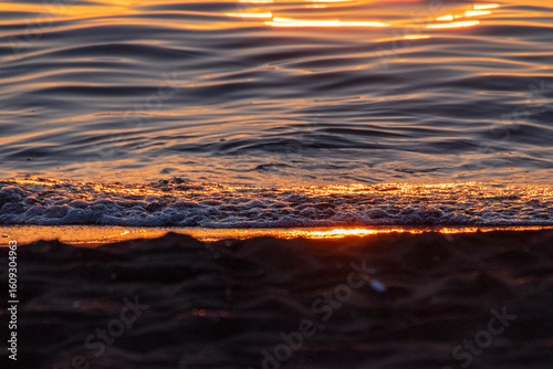 A serene, abstract close-up of a Black Sea sunset. Shimmering golden light reflects on dark, rippling water, creating a tranquil and atmospheric scene on the picturesque Georgian coast.