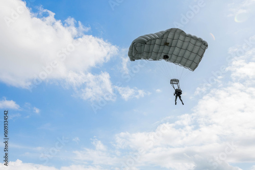 Skydiver in Action,  A skydiver gliding through the blue sky with a fully deployed parachute, showcasing the thrill and freedom of airborne adventure.
