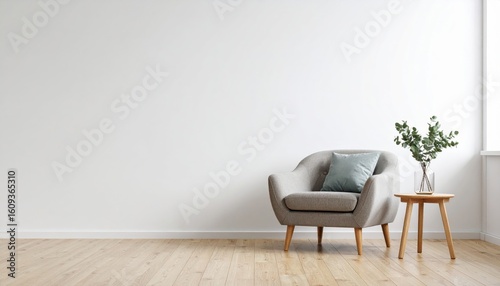 A minimalist living space features a modern gray armchair with a cushion, next to a small wooden side table holding a glass vase with green foliage.