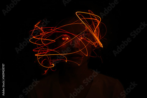 Portrait of a face illuminated by fire lines in the dark, Abstract portrait with red light trail effect on a woman's face