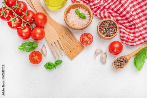 Fotografía Assorted cooking ingredients with tomatoes, spices, and kitchen tools on white background with red cloth