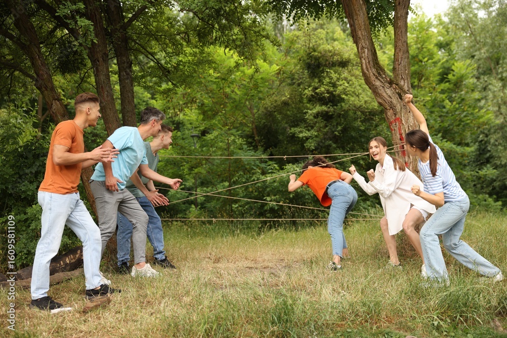Fototapeta premium Team building. Group of happy people playing spider web game outdoors