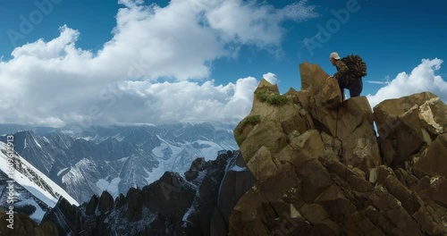 Man with a backpack conquering a peak against the backdrop of mountains.