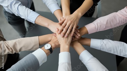 Teamwork: Diverse adults huddle hands together in unity and success, showing collaboration