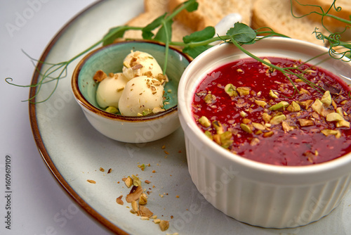 Deliciously Crafted Dessert Featuring Berry Coulis, Creamy Topping, and Crunchy Nuts Served Alongside Toasted Bread for a Gourmet Experience