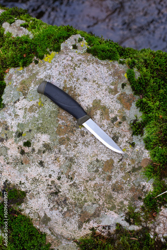 camping knife on a stone near a river