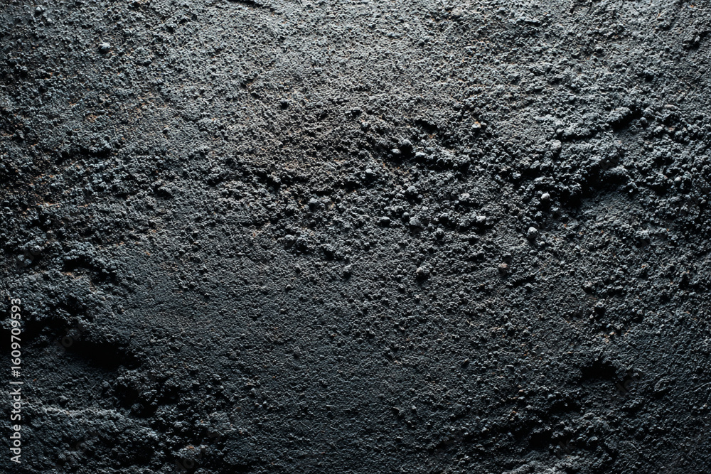 Obraz premium A dark, rough, and textured concrete surface with a gritty appearance, suitable for grunge or industrial backgrounds