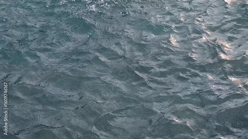 Abstract water surface background: slow motion of blueish water waves outdoors