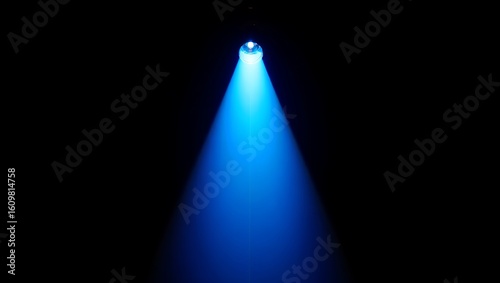 A single bright blue spotlight beam cuts through the darkness creating a dramatic and focused illumination effect