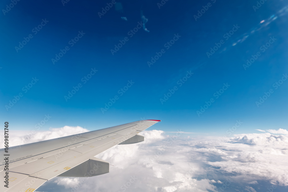 Fototapeta premium View from the airplane window at a beautiful cloudy sky and the airplane wing