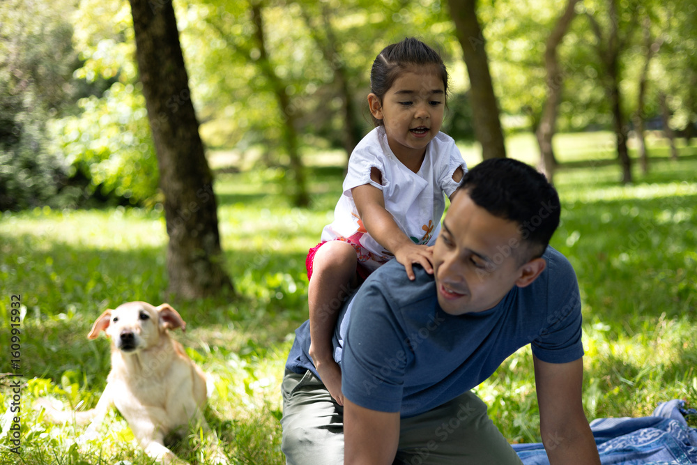 Fototapeta premium Happy latin family enjoying a sunny day at the park with their dog