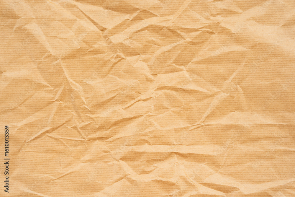 Obraz premium Crumpled brown kraft paper with visible creases and textured surface. Suitable for design projects, packaging mockups, or backgrounds
