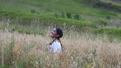 Indigenous woman wearing traditional clothes embracing nature in a field