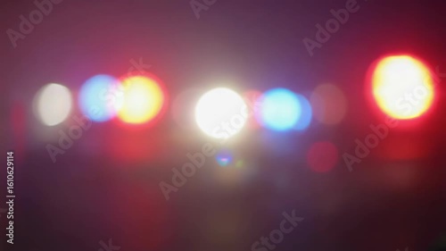 Blurry bokeh effect of flashing emergency vehicle lights on nighttime roadway