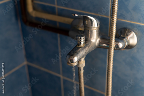 Shower faucet covered with limescale, flowing water close up shot.