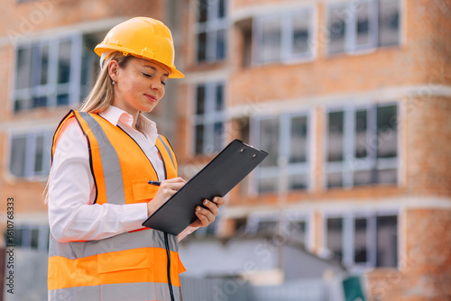 Tableau sur toile Female Construction Worker Inspecting Project with Clipboard and Safety Gear