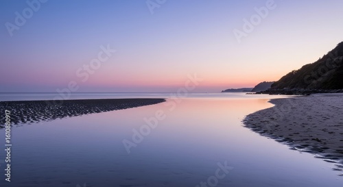 Serene Beach at Dusk: Pastel Sky Reflections on Tranquil Water and Dark Sand