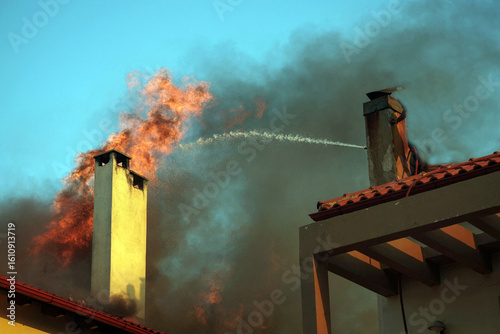 Foto extinguishing flames from burning house during kryoneri wildfire