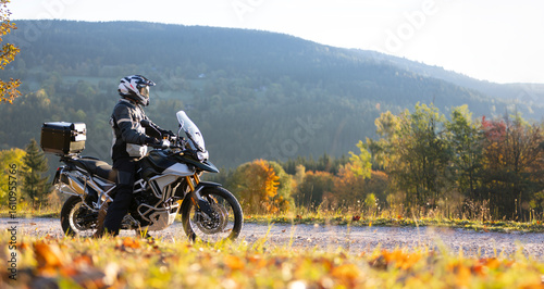Driver posing on motorcycle during sunrise, rural countryside